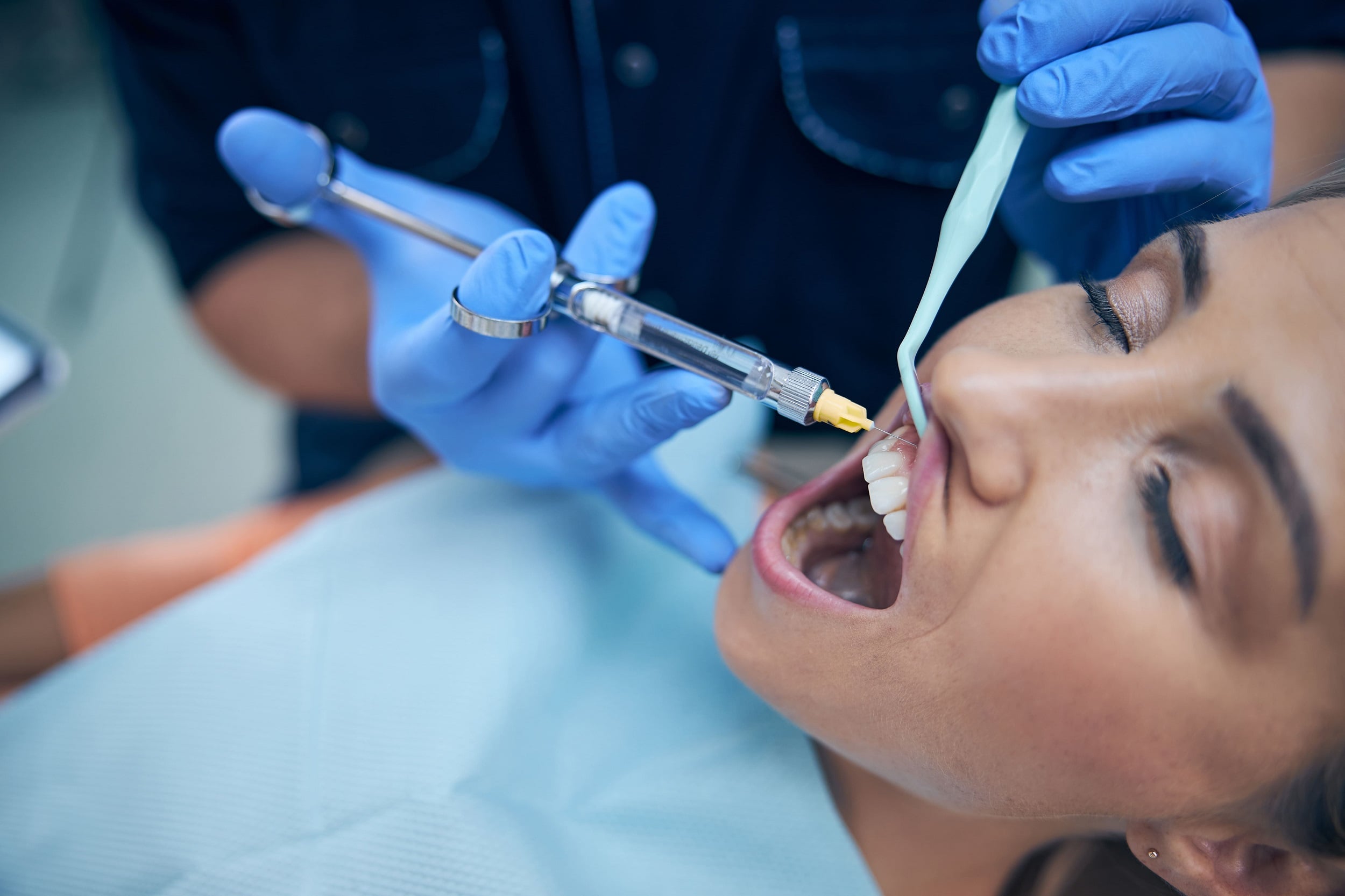 dentist-doing-injection-in-woman-gum-in-office-2023-11-27-05-36-27